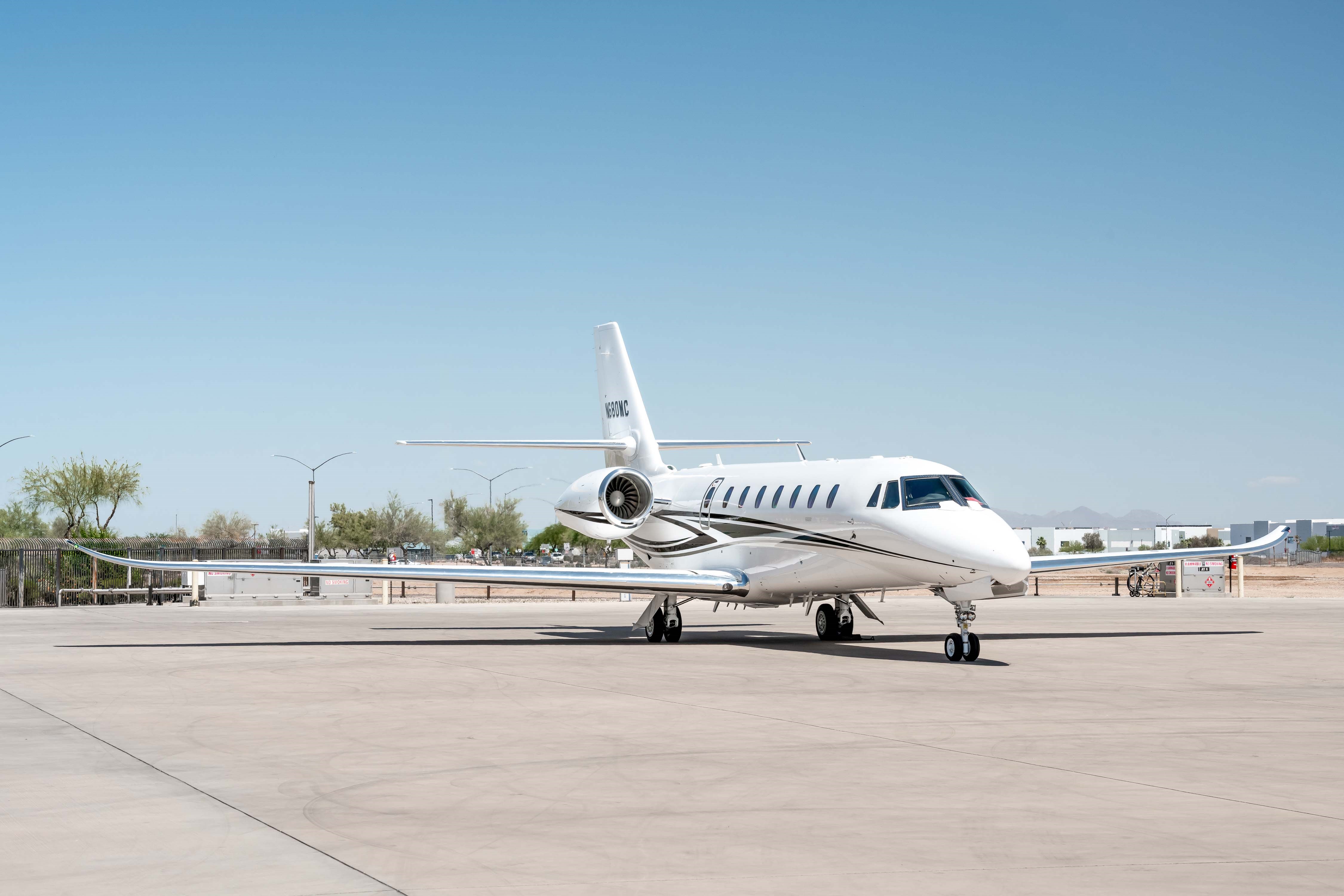 A front three-quarter view of a white Cessna Citation Latitude business jet, registration N680MC, parked on a sunny tarmac.